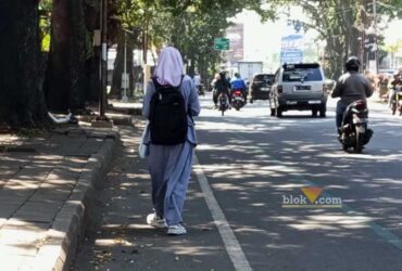 Salah seorang pejalan kaki di bahu jalan raya (Satria Akbar Sigit/Blok-a.com)