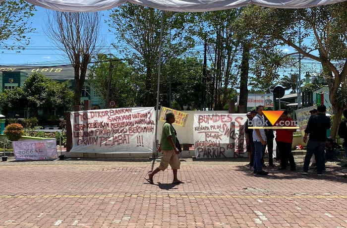 Banner penolakan gerai Alfamart yang ada di area RSUD Kanjuruhan dan pengelolaan parkir yang akan dikerjasamakan dengan pihak ketiga (blok-a.com/Putu Ayu Pratama S)