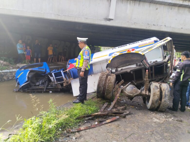 Teks: Kondisi truk tangki bermuatan solar yang terperosok ke sungai di bawah jembatan tol JoMo.(Foto: Dokumen PJR 3 Polda Jatim)