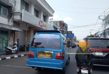 Angkot Pelajar Gratis di Kota Malang Mulai Beroperasi Senin, 90 Unit Disiapkan Kota Malang, blok-a.com – Program angkutan pelajar gratis di Kota Malang direncanakan mulai beroperasi pada Senin (31/8/2026). Dinas Perhubungan (Dishub) Kota Malang kini menyiapkan para pengemudi yang akan terlibat dalam layanan tersebut. Sebelum layanan berjalan, Dishub terlebih dahulu melakukan sosialisasi kepada para pengemudi, termasuk mengenai standar operasional prosedur (SOP) layanan angkutan pelajar gratis. “Konsepnya yang pertama kita lakukan sosialisasi dulu. Yang jelas kita lakukan sosialisasi SOP kepada seluruh pengemudi yang terlibat nanti di layanan angkutan pelajar,” ujar narasumber. Untuk tahap sosialisasi, Dishub sementara mengundang sekitar 60 hingga 70 pengemudi. Namun, jumlah armada yang dibutuhkan untuk menjalankan program tersebut lebih banyak. “Kita membutuhkan 90. Maksimal 90, 90 unit gitu,” jelasnya. Nantinya, tidak seluruh angkot yang disiapkan bisa langsung bergabung. Sebab, masih terdapat sejumlah kendaraan yang harus menyelesaikan proses administrasi dan kelayakan kendaraan, termasuk uji KIR. “Mereka kan butuh Uji KIR juga, ada yang belum,” katanya. Sementara itu, dari sisi perangkat pendukung, sebanyak 73 angkot disebut telah terpasang GPS. Perangkat tersebut menjadi bagian dari sistem pemantauan angkot yang digunakan dalam layanan angkutan pelajar gratis. Jika seluruh persiapan berjalan sesuai rencana, layanan angkot pelajar gratis tersebut ditargetkan mulai berjalan Senin (31/8/2026). “Jalan nanti. Senin insyaallah,” ujarnya. Untuk rutenya, Dishub tidak membuat jalur baru secara keseluruhan. Angkot pelajar gratis akan mengikuti rute yang sebelumnya digunakan bus sekolah. “Rutenya sesuai dengan rutenya bus sekolah,” jelasnya. Saat ini, layanan bus sekolah di Kota Malang memiliki 15 jalur. Rute angkot pelajar gratis nantinya juga akan disesuaikan dengan kebutuhan pelajar, termasuk menjangkau kawasan yang sebelumnya menjadi perhatian dalam layanan bus sekolah. Salah satunya kawasan Madyopuro. Selain itu, wilayah Buring juga menjadi bagian dari cakupan layanan tersebut. “Ya, ditambah lagi tuh. Ya termasuk itu,” katanya. Dengan skema tersebut, angkot pelajar gratis diharapkan tidak hanya mengantarkan pelajar menuju sekolah, tetapi juga memperluas jangkauan layanan transportasi pelajar di sejumlah kawasan Kota Malang.